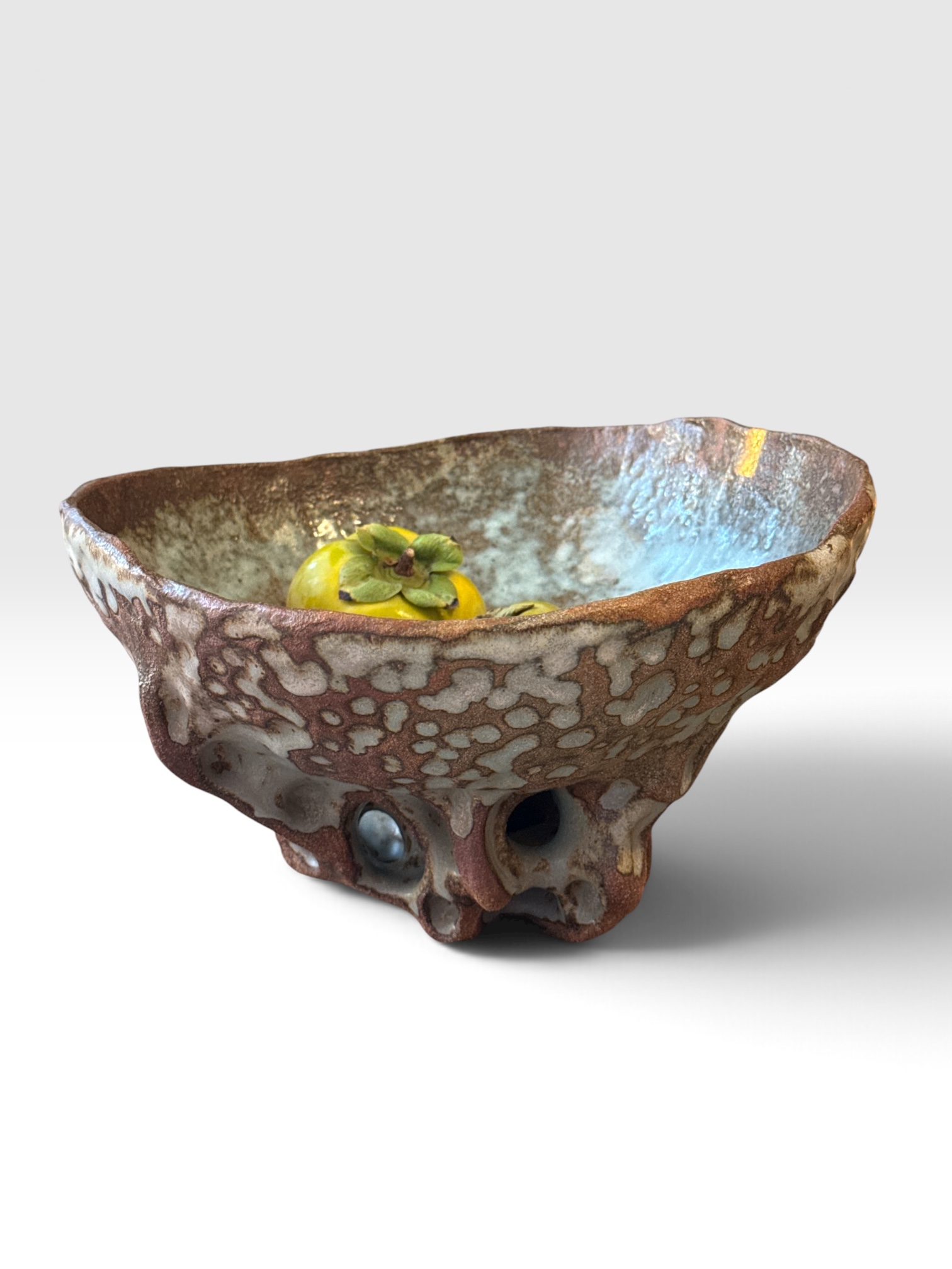 Earthy patterned ceramic bowl with a pale blue interior and an open sculptural base